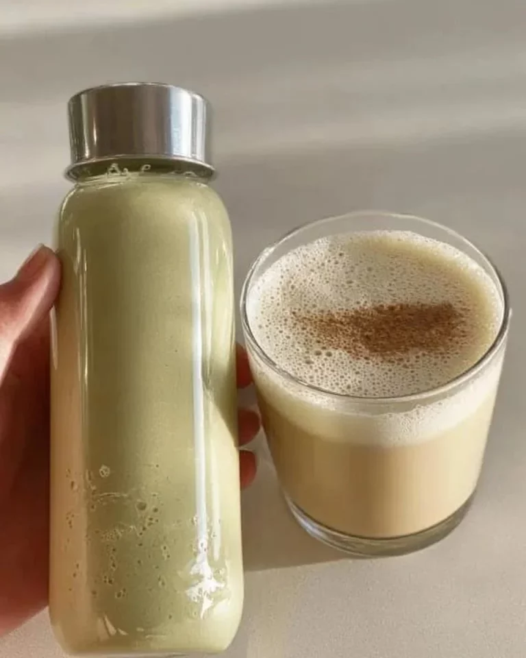 Homemade pistachio milk in a glass with a handful of pistachios beside it.