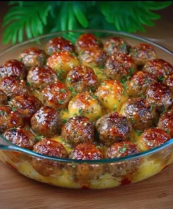 Baked potato and meatball dish topped with cheese and herbs, ready to serve.