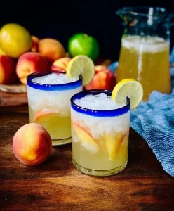 A refreshing glass of Tipsy Peach Lemonade garnished with peach slices.
